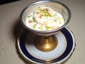 Creamy rasmalai with milk and pistachios served in a decorative glass bowl